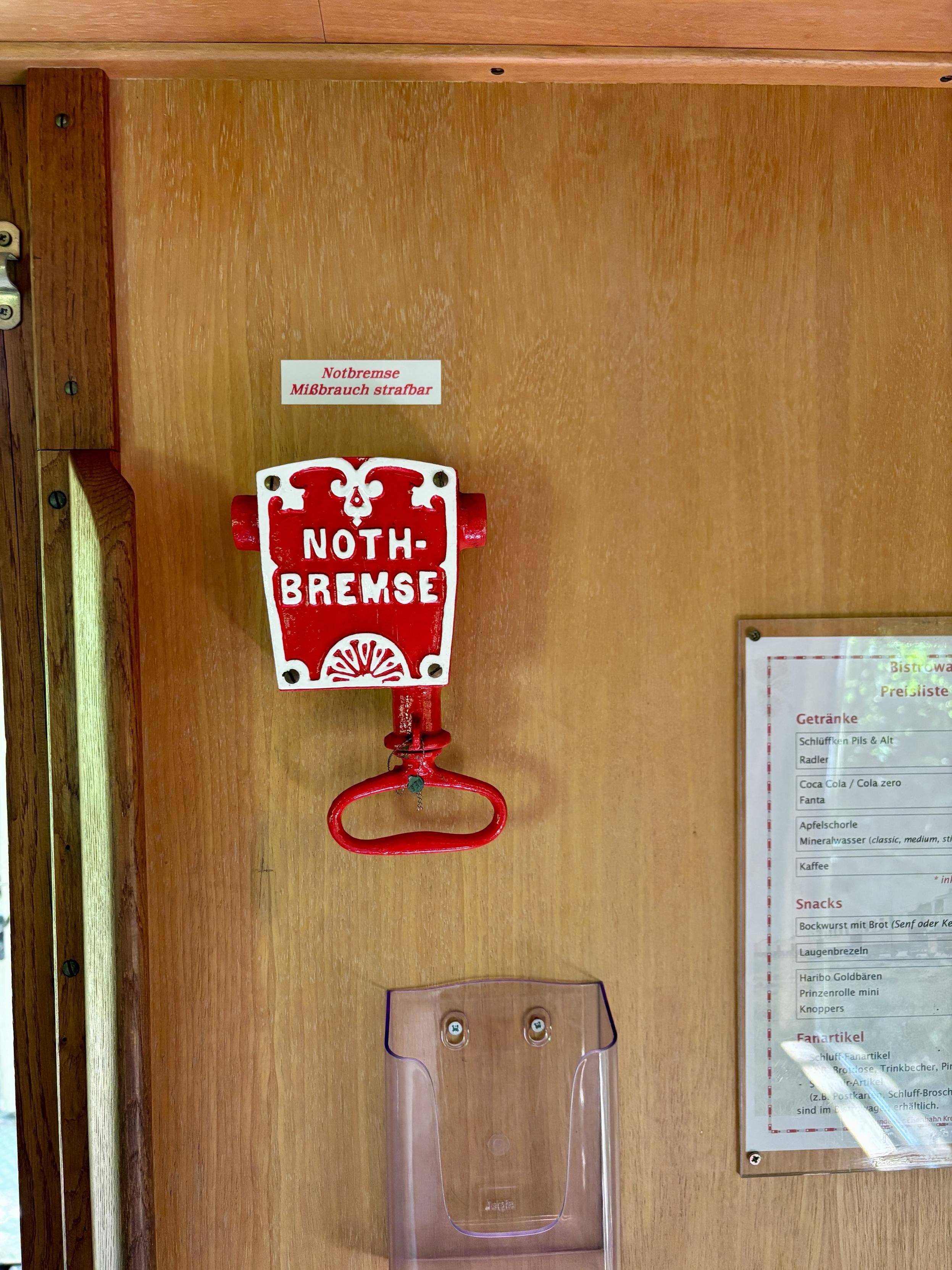 An interior wooden wall features a red emergency brake mechanism labeled 
