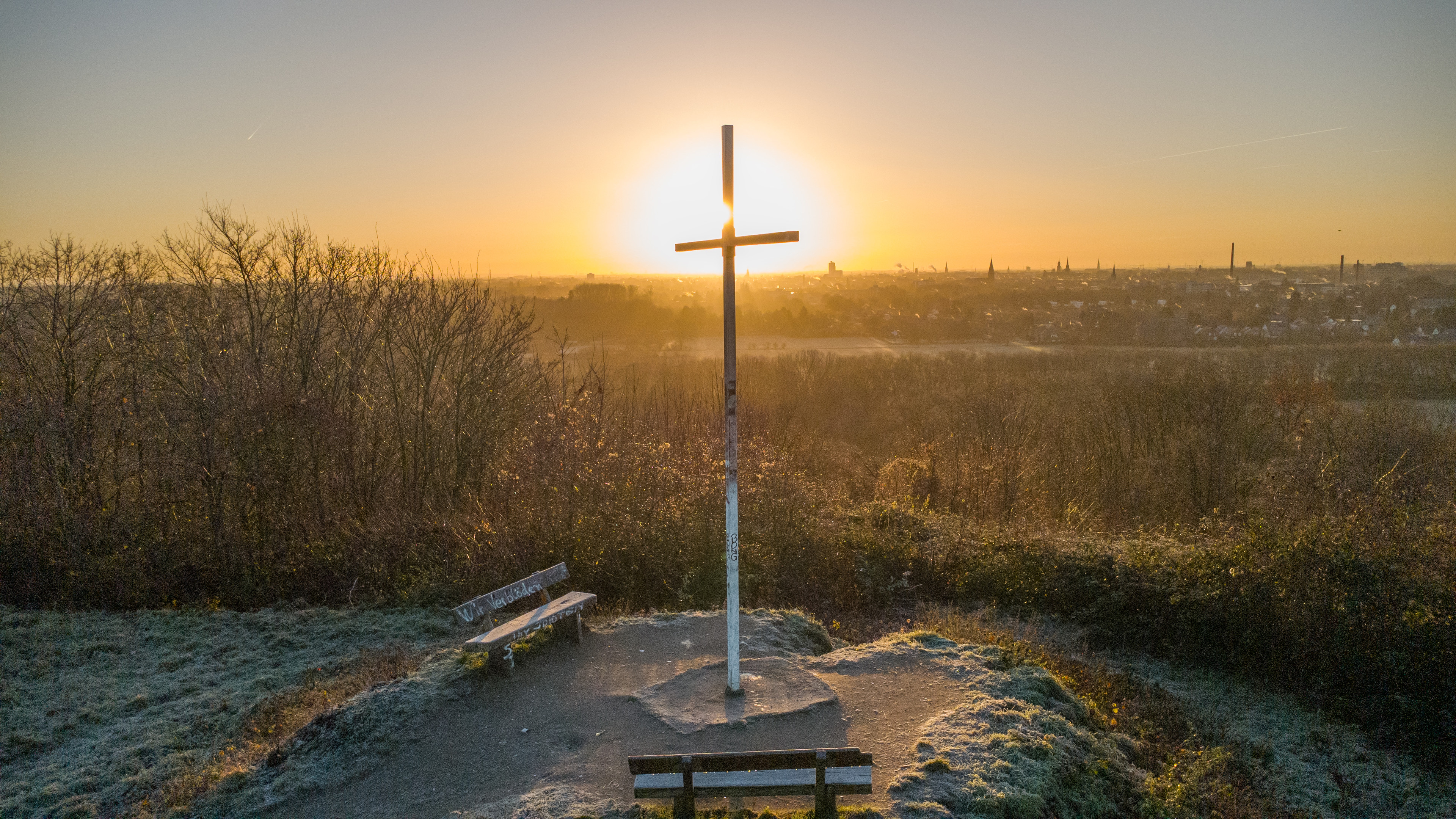 Ein Gipfelkreuz auf einem Berg im Sonnenaufgang.